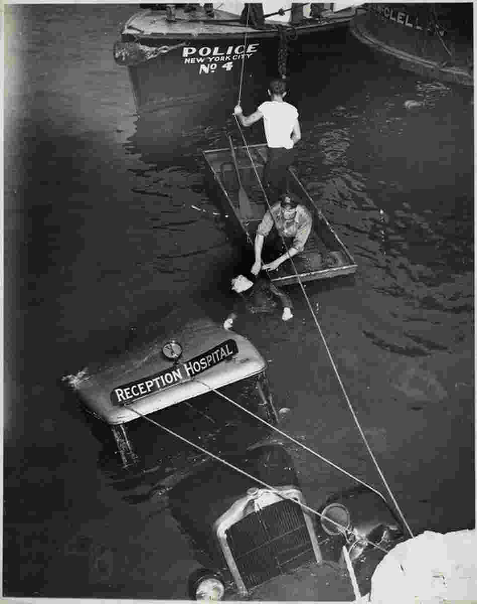 [Police officer and assistant removing body of Reception Hospital ambulance driver. Morris Linker from East River, New York], Aug. 24, 1943