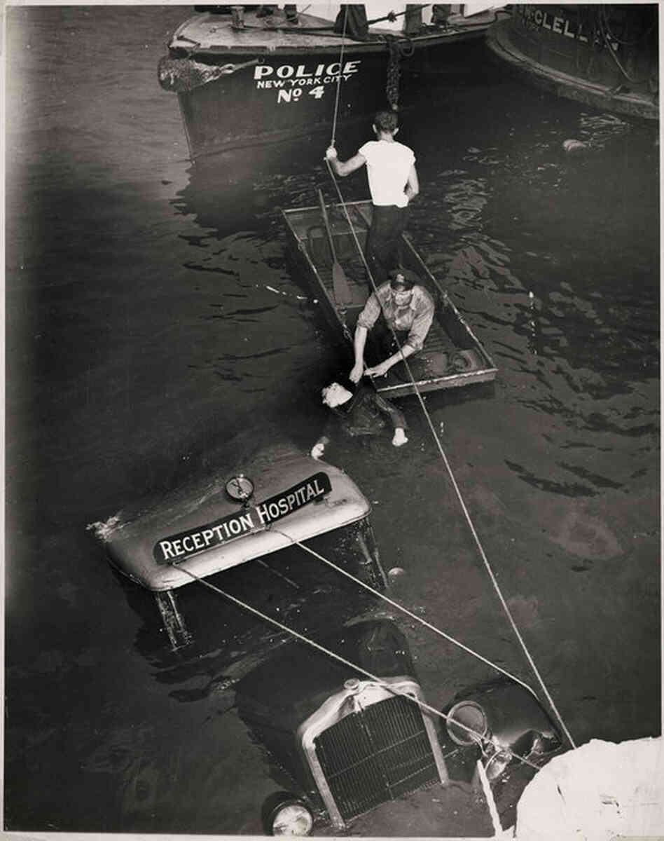[Police officer and assistant removing body of Reception Hospital ambulance driver. Morris Linker from East River, New York], Aug. 24, 1943