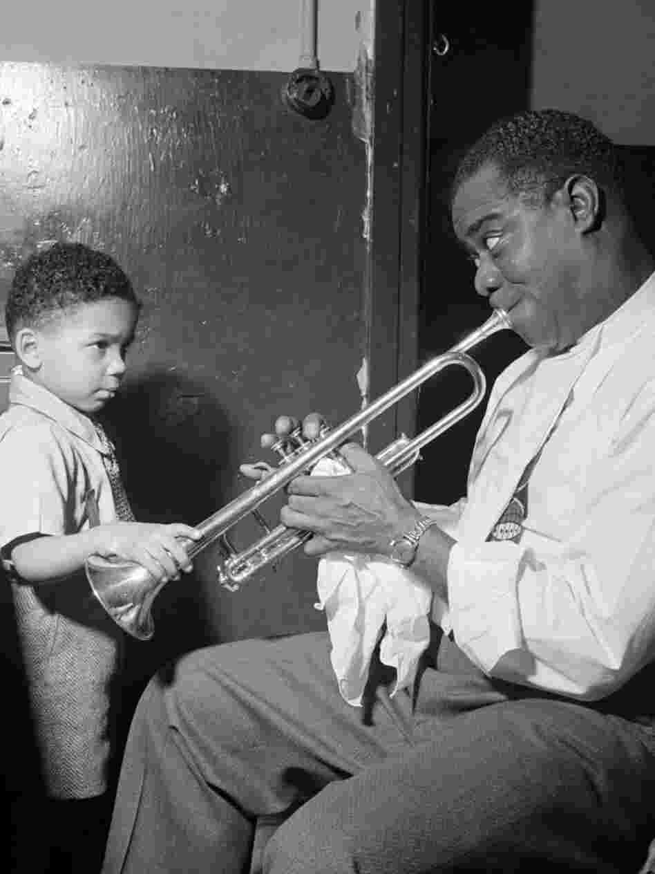 Louis Armstrong entertains a young fan backstage.
