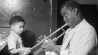 Louis Armstrong entertains a young fan backstage. Louis Armstrong entertains a young fan backstage.