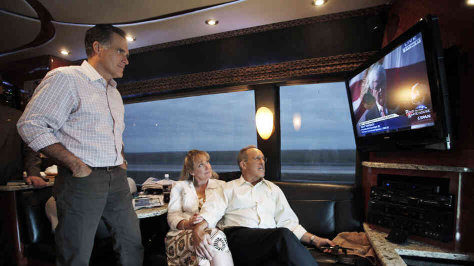 Mitt Romney watches his GOP rival Newt Gingrich on TV as he rides his campaign bus on Sunday with his brother Scott and sister-in-law Sheri. Using the power of television — through ads and debates — was a key part of Romney's strategy in Florida.