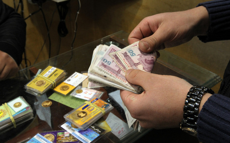 An Iranian man counts banknotes after exchanging a gold coin for cash in Tehran. An Iranian man counts banknotes after exchanging a gold coin for cash in Tehran.