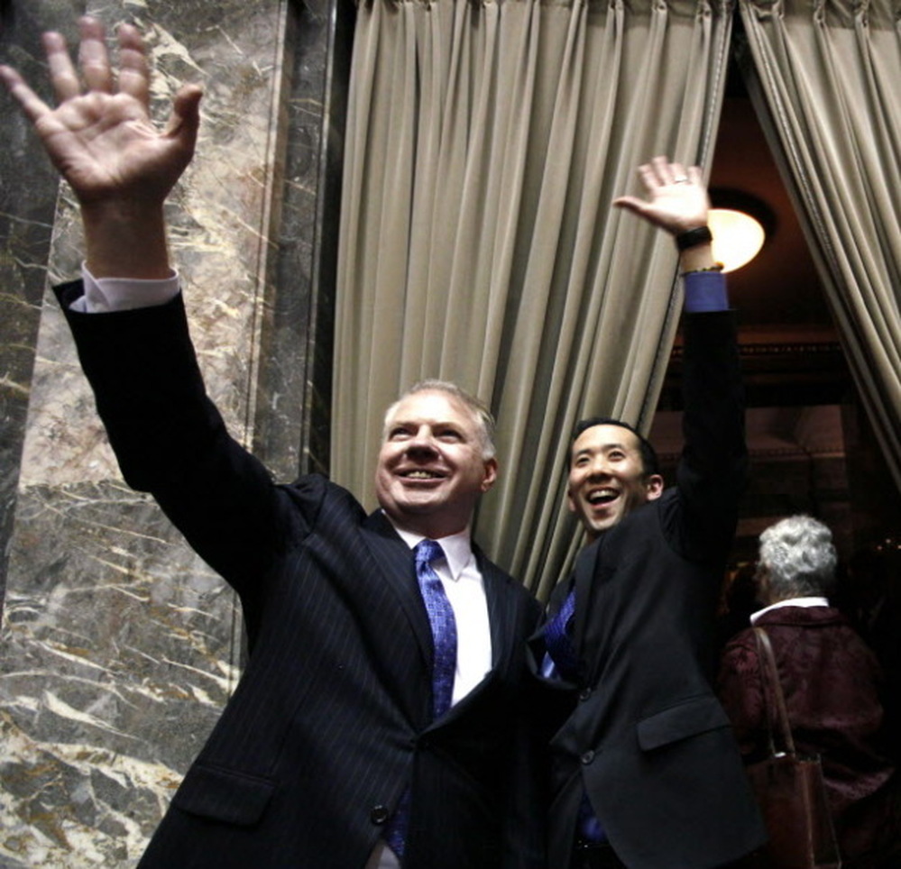 Sen. Ed Murray, D,, left, and his partner Michael Shiosaka wave at spectators in the upper gallery after the Washington state Senate voted for a proposal to legalize same-sex marriage.