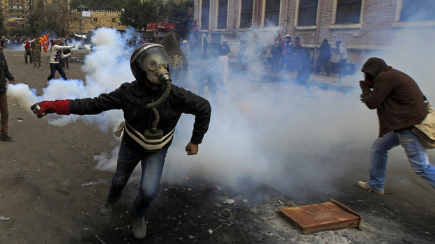 In Cairo earlier today, a masked Egyptian protester prepared to throw back a tear gas canister fired by security forces.