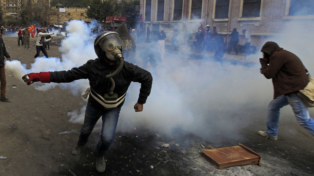 In Cairo earlier today, a masked Egyptian protester prepared to throw back a tear gas canister fired by security forces.