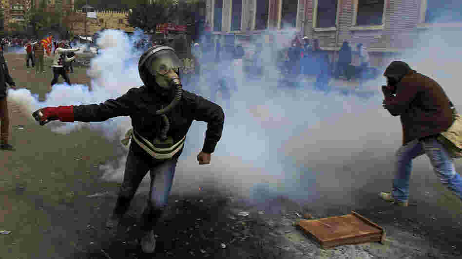 In Cairo earlier today, a masked Egyptian protester prepared to throw back a tear gas canister fired by security forces.
