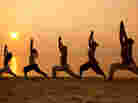 Five people on a beach stand in the warrior pose. Five people on a beach stand in the warrior pose.