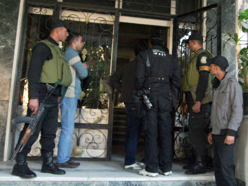 Members of the Egyptian military stand guard as officials raid the offices of a nongovernmental organization in Cairo. Egyptian investigating judges referred international NGO workers to trial for allegedly being involved in banned activities and illegally receiving foreign funds, security officials said. 