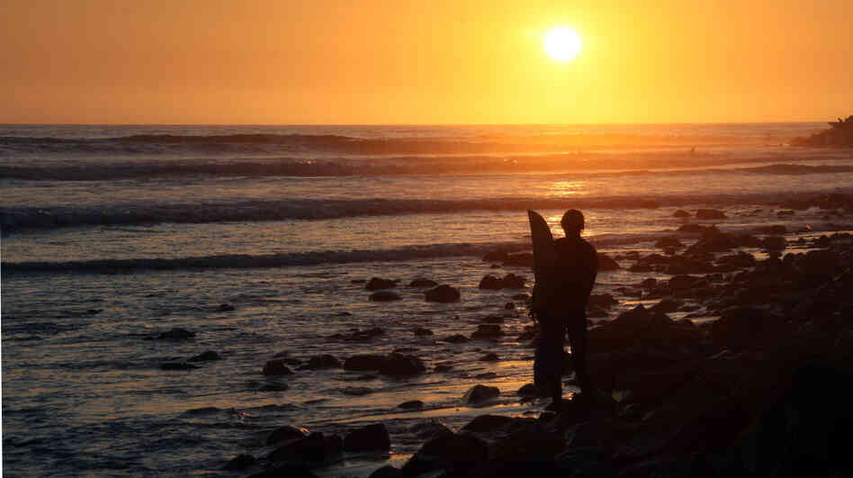 A surfer watches the waves just before sunset at Will Rogers State Beach in the Pacific Palisades area of Los Angeles.