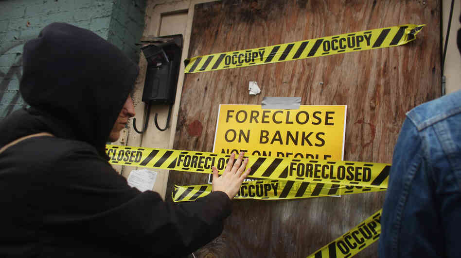 A member of the Occupy Wall Street movement places tape over a window of a foreclosed home during a march in the impoverished community of East New York in Brooklyn in December. A member of the Occupy Wall Street movement places tape over a window of a foreclosed home during a march in the impoverished community of East New York in Brooklyn in December.