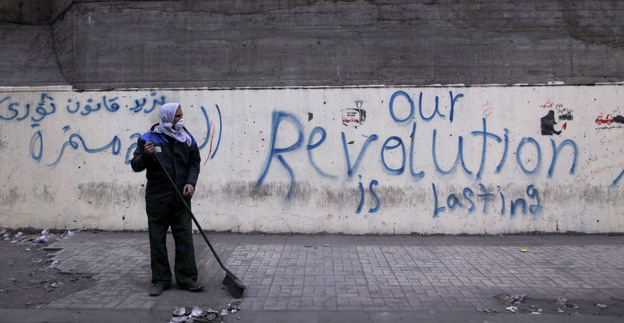 A municipal worker cleans a sidewalk Tuesday at the site of recent clashes between protesters and security forces near the Interior Ministry in Cairo