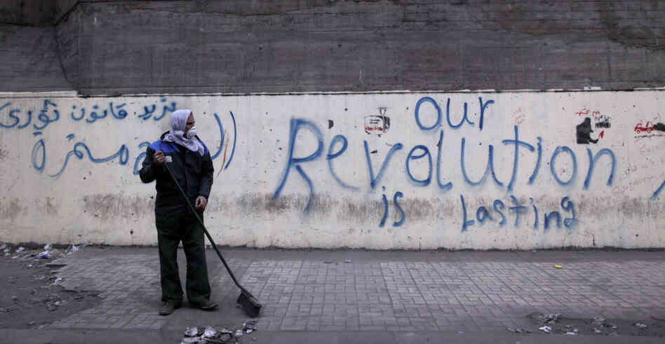 A municipal worker cleans a sidewalk Tuesday at the site of recent clashes between protesters and security forces near the Interior Ministry in Cairo