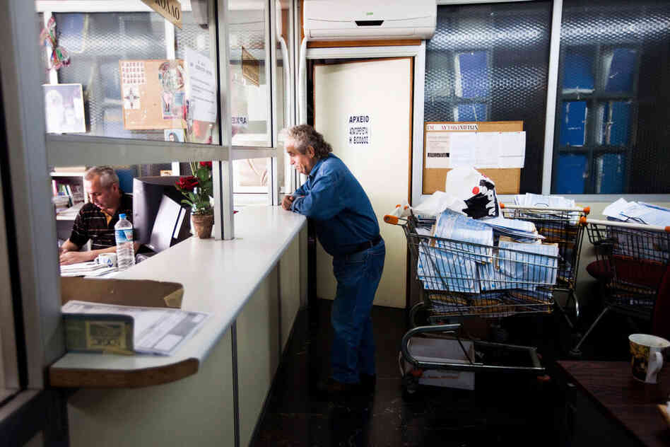 A man waits at a window at Athens' central tax office, which is filled with shopping carts full of tax papers left to be filed.