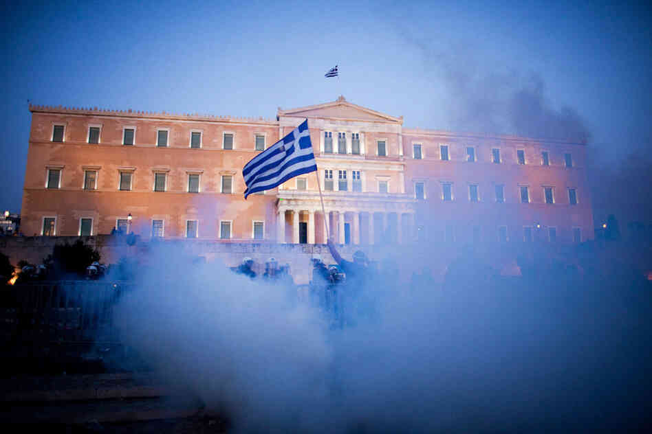 A protester holds up a Greek flag in front of the parliament building during anti-austerity demonstrations in Athens last summer.