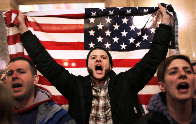 For so many reasons, Americans are seething. Here, a protester shouts as he holds an American flag after storming the Wisconsin state Capitol in Madison last March, after Republicans in the state Senate voted to curb collective bargaining rights for public workers.
