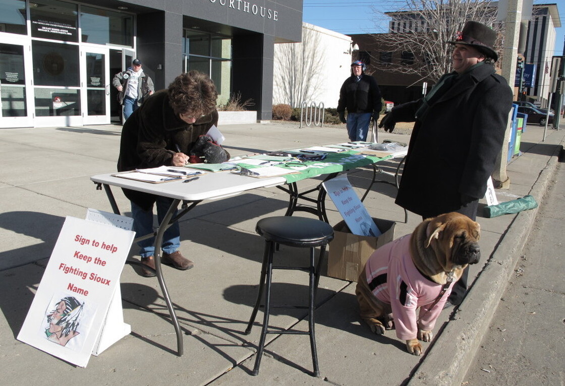 Charles Tuttle, a backer of the University of North Dakota's Fighting Sioux nickname, watches as a woman signs petitions supporting the nickname on Tuesday, Feb. 7.