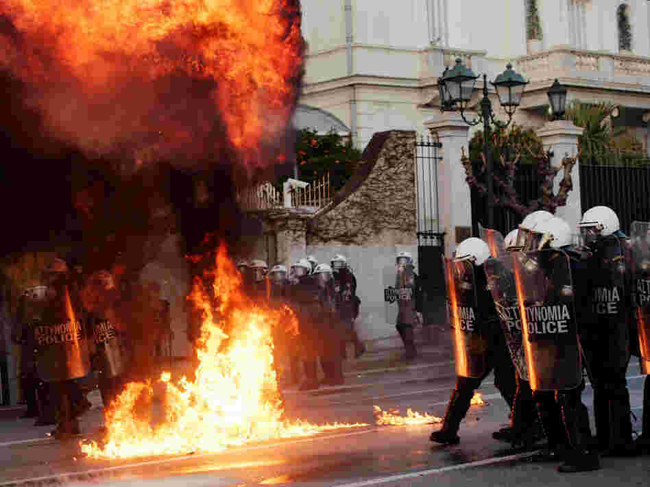 Greek demonstrators throw fire bombs towards riot police during violent protests in central Athens on February 12.
