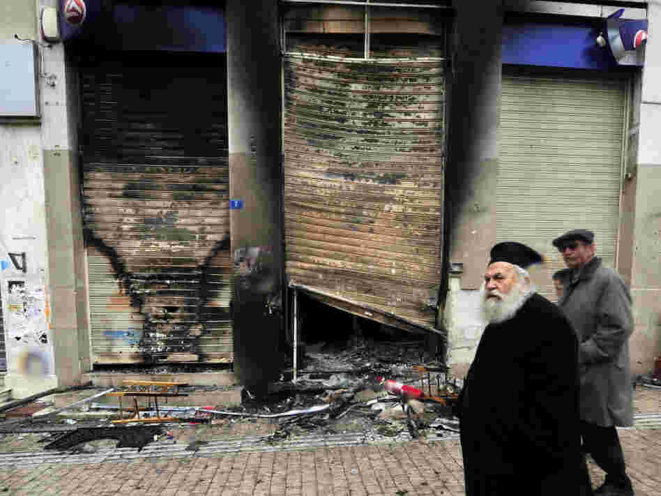 A Greek priest walks past a burned branch of the Eurobank in central Athens on February 13.