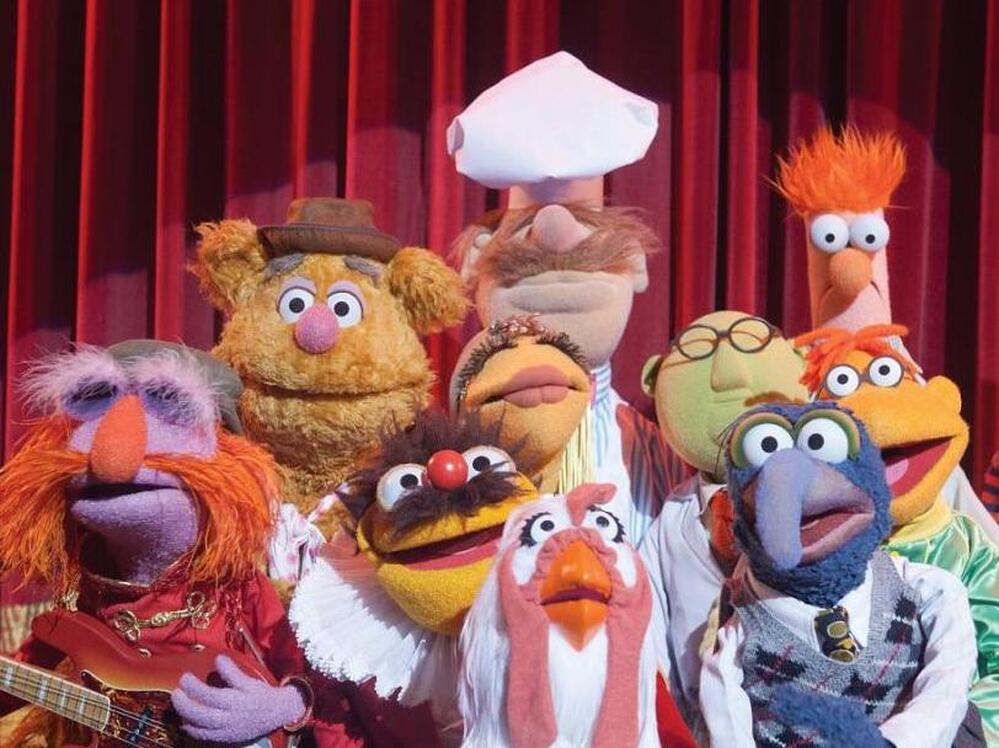 The cast of The Muppets includes (left to right) Floyd Pepper, Fozzie Bear, Lew Zealand, Janice, Swedish Chef, Camilla The Chicken, Dr. Bunsen Honeydew, Gonzo, Scooter and Beaker.