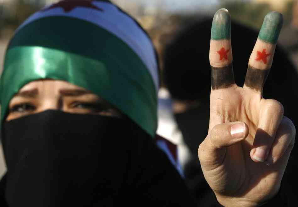 A woman flashes the V for 'victory' sign with her fingers painted in the colors of the former Syrian flag during a protest against the Syrian regime outside Damascus' embassy in Kuwait City on Feb. 5, 2012. A woman flashes the V for 'victory' sign with her fingers painted in the colors of the former Syrian flag during a protest against the Syrian regime outside Damascus' embassy in Kuwait City on Feb. 5, 2012.