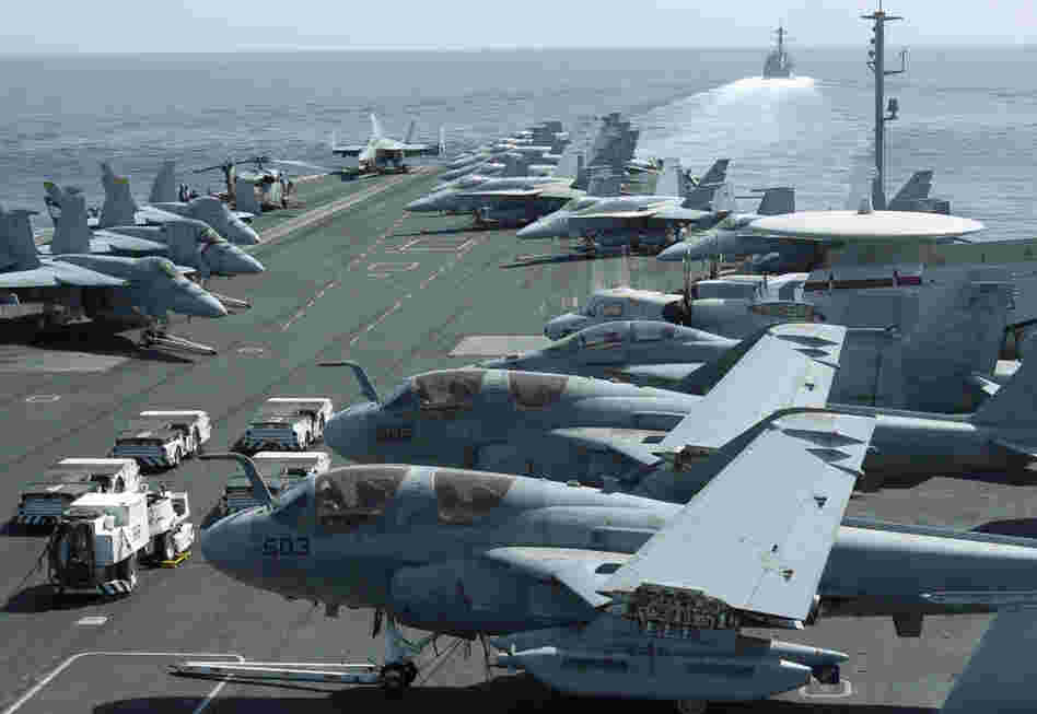 The USS Abraham Lincoln sailed from the Persian Gulf through the Strait of Hormuz on Tuesday. This photo was taken from the bridge of the aircraft carrier and shows U.S. aircraft parked on its flight deck. In the background, a U.S. destroyer patrols.
