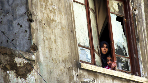 The fighting in Syria was seen as a spark for clashes in the Lebanese city of Tripoli last week. Here a Lebanese woman and her daughter look out the window of their bullet-pocked home in Tripoli on Sunday, Feb. 12.  