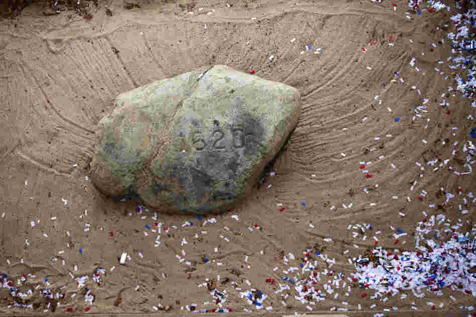 Thanksgiving parade confetti litters the sand around Plymouth Rock in Massachusetts, the landing place of the Mayflower Pilgrims in 1620.
