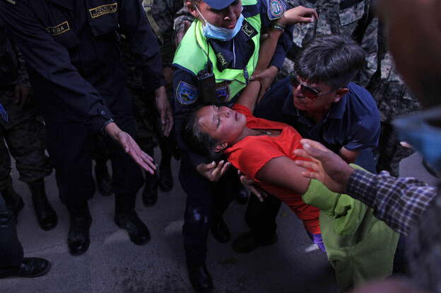 A woman is taken away by police after fainting during clashes when relatives of inmates killed during last week's prison fire stormed the restricted area of the morgue in Tegucigalpa, Honduras on Monday. 