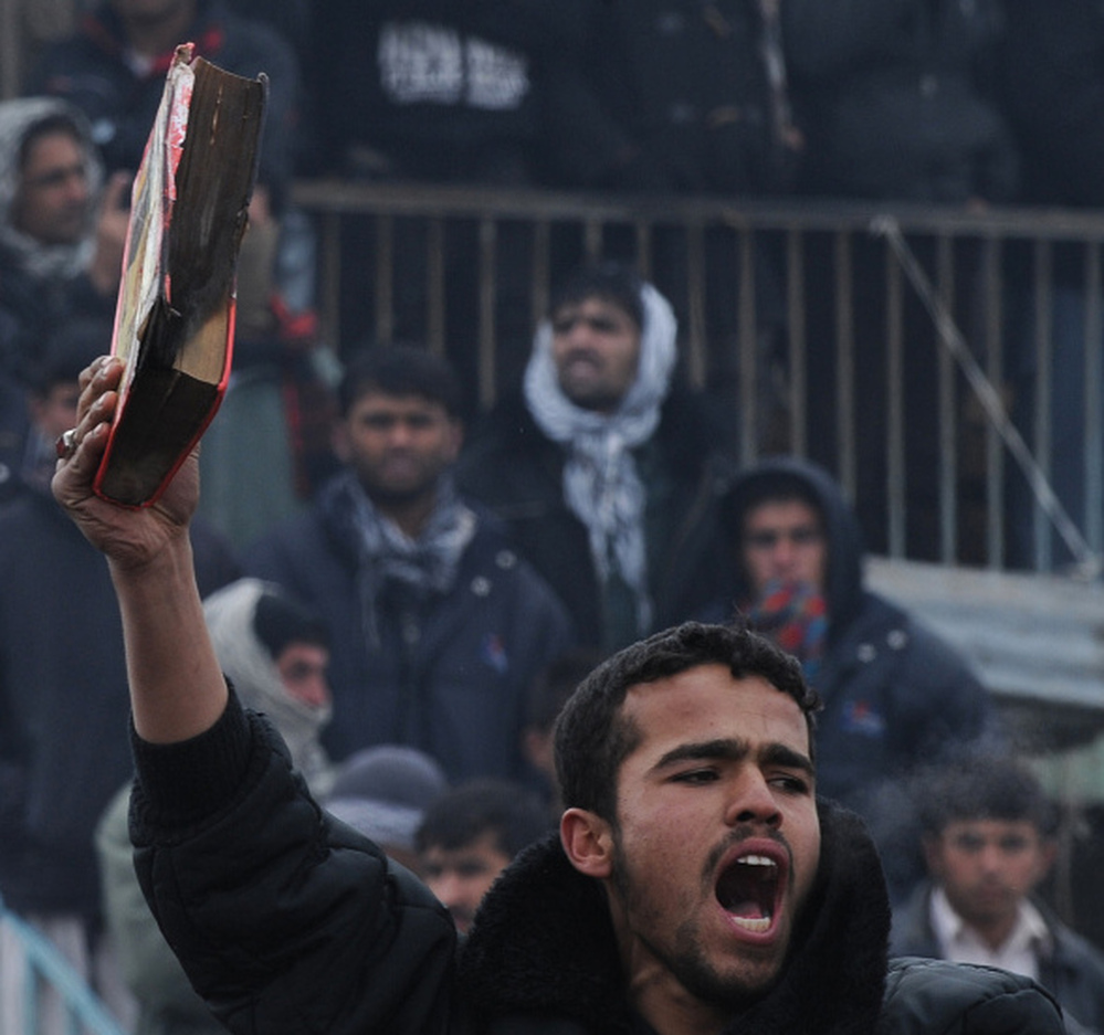 An Afghan demonstrator holds a copy of a half-burnt Quran, allegedly set on fire by soldiers at Bagram Air Field, during a protest outside the base today. 