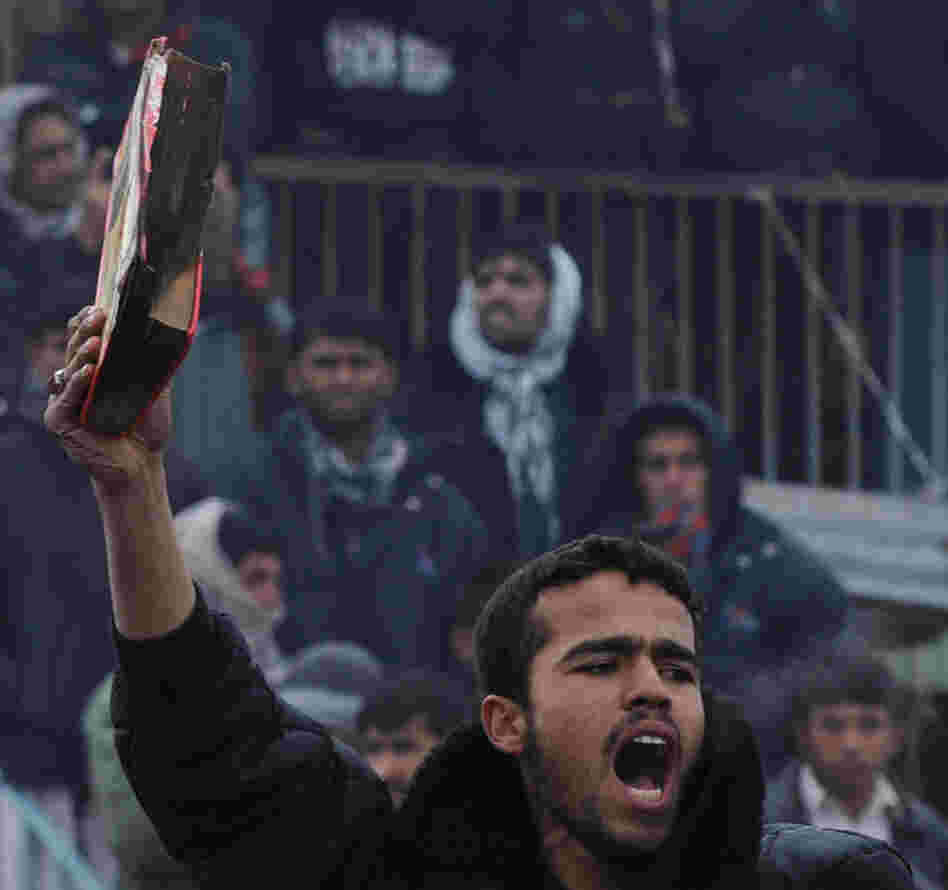 An Afghan demonstrator holds a copy of a half-burnt Quran, allegedly set on fire by soldiers at Bagram Air Field, during a protest outside the base today. 