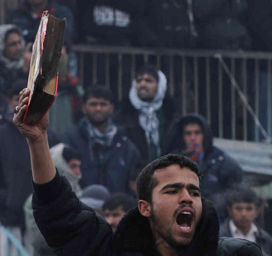 An Afghan demonstrator holds a copy of a half-burnt Quran, allegedly set on fire by soldiers at Bagram Air Field, during a protest outside the base today. 