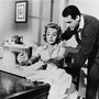 American actress Donna Reed sews on sewing machine as American actor Carl Betz watches over her shoulder