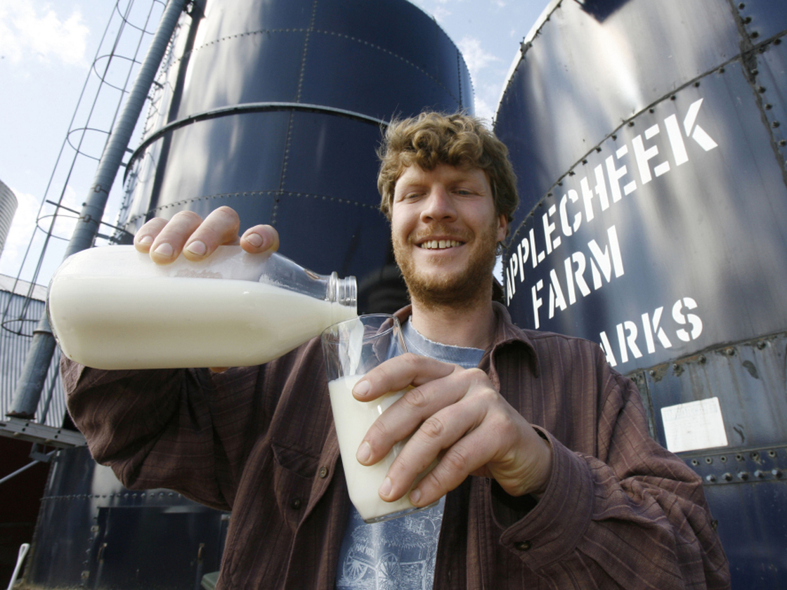 John Clark pours raw milk into a glass at Applecheek Farm in Hyde Park, Vt.