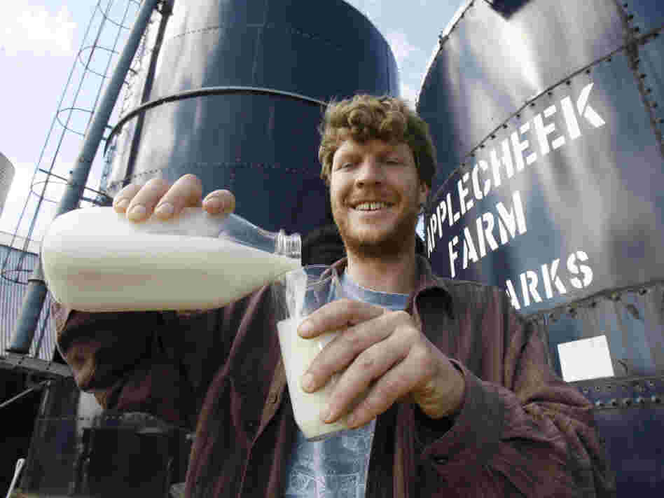 John Clark pours raw milk into a glass at Applecheek Farm in Hyde Park, Vt.