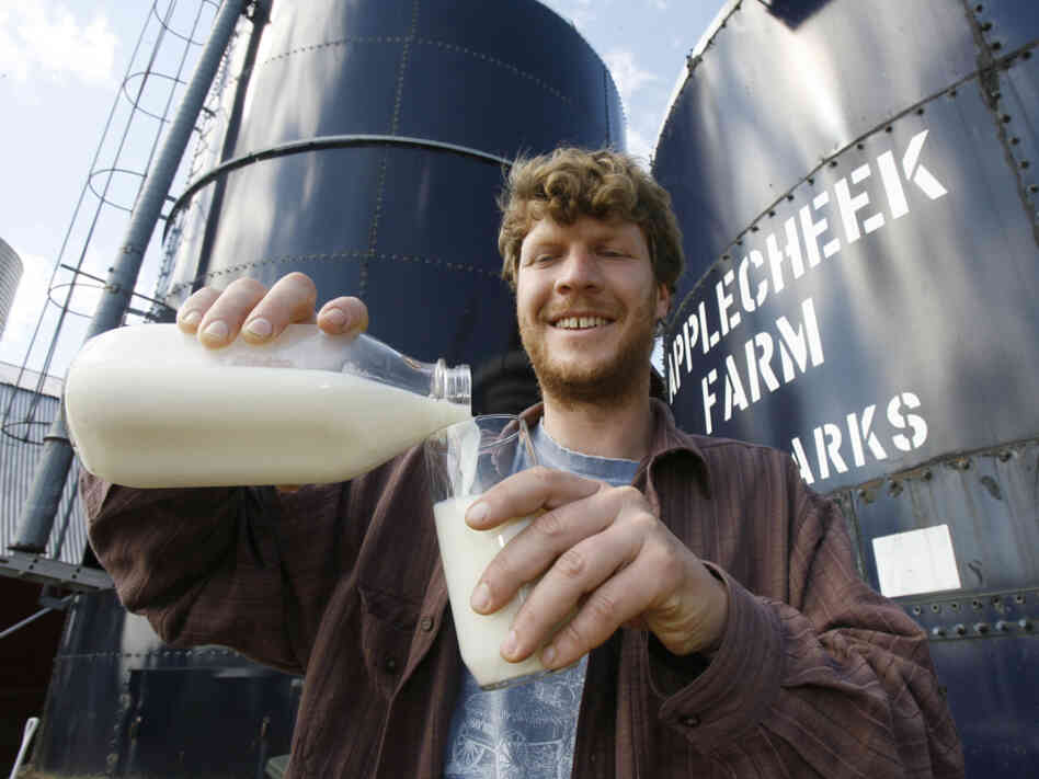 John Clark pours raw milk into a glass at Applecheek Farm in Hyde Park, Vt.
