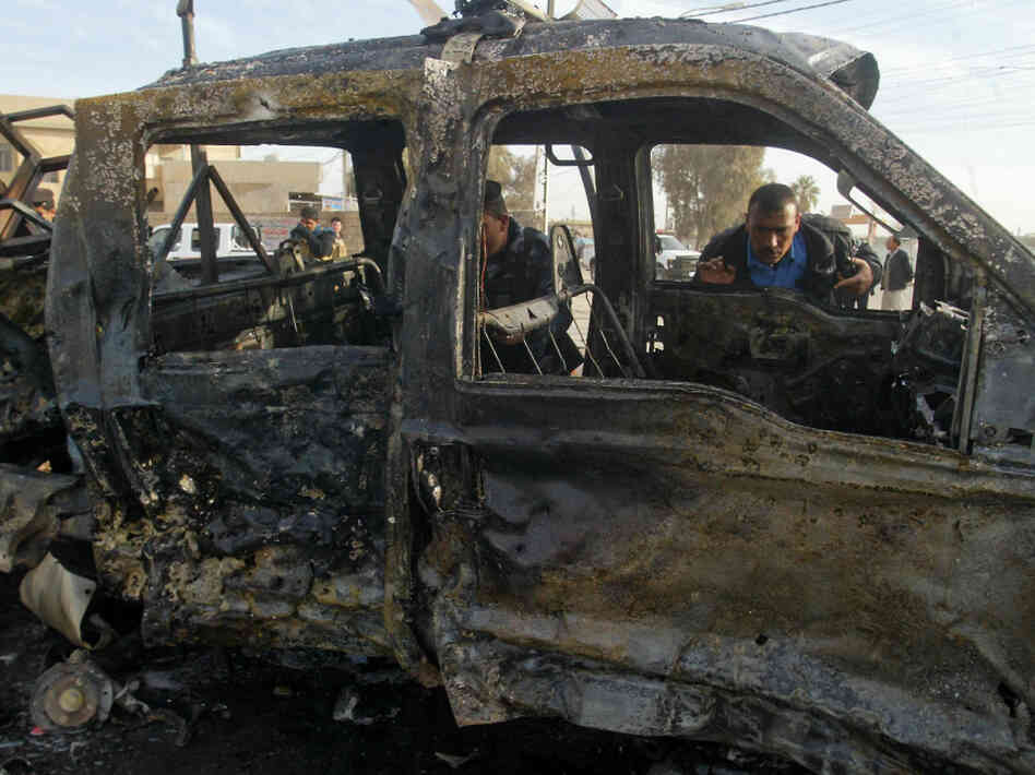 An Iraqi policeman inspects a destroyed vehicle at the site of a blast in the northern city of Kirkuk earlier today (Feb. 23, 2012).