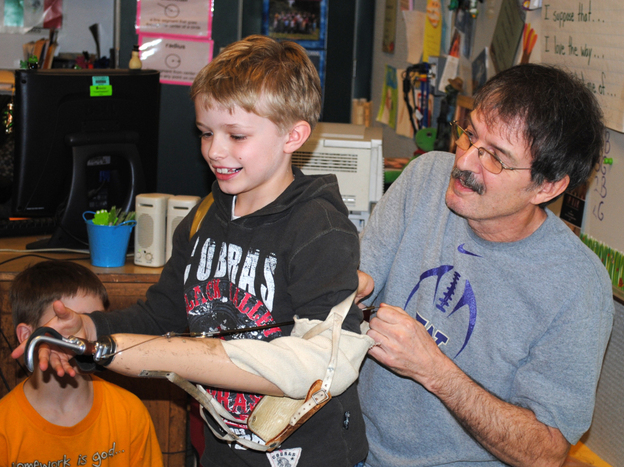 Ron Cushman's 8-year-old grandson, Shaun, tries out his grandfather's prosthetic arm. Cushman would let his students try out the arm on the first day of school.