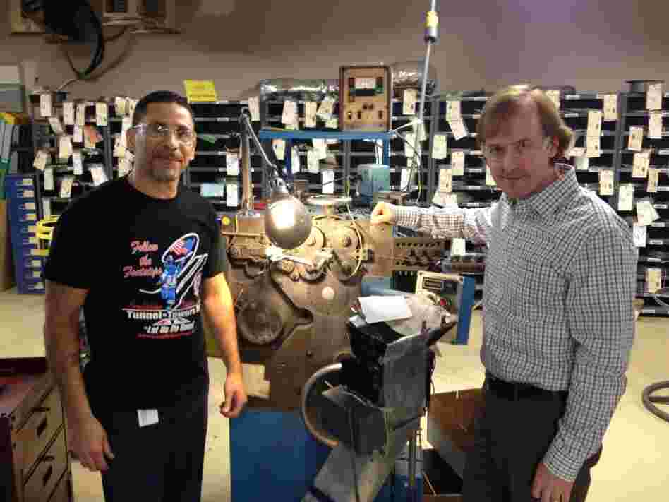 Juan Delgado (left) and Steve Kempf of Brooklyn's Lee Spring company stand with a 50-year-old coiling machine, still in use today.