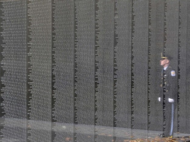 An officer is reflected on the Vietnam Veterans Memorial during a ceremony for Veterans Day in 2011.