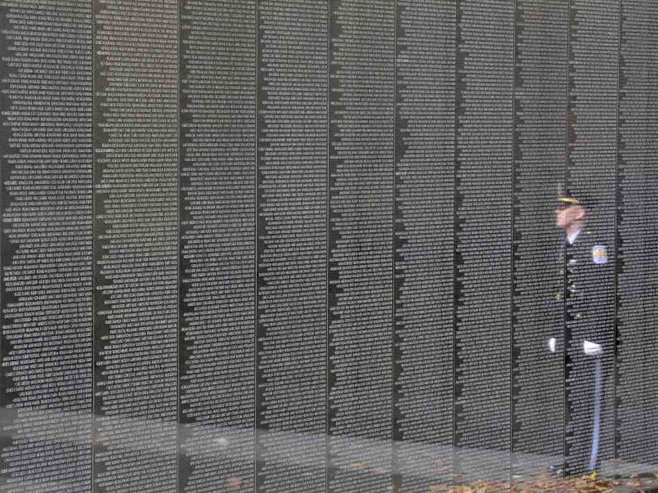 An officer is reflected on the Vietnam Veterans Memorial during a ceremony for Veterans Day in 2011.