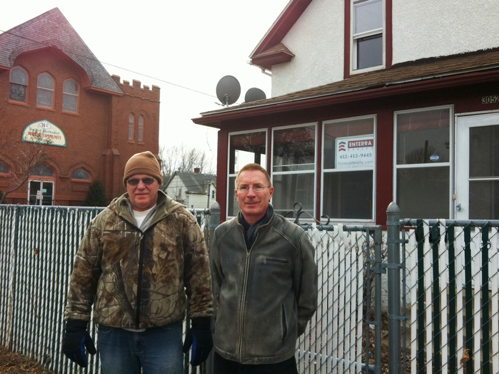 Dan Grohs (left) with real estate agent Pat Paulson in front of a foreclosed Minneapolis home. Grohs hopes to buy the house with cash.