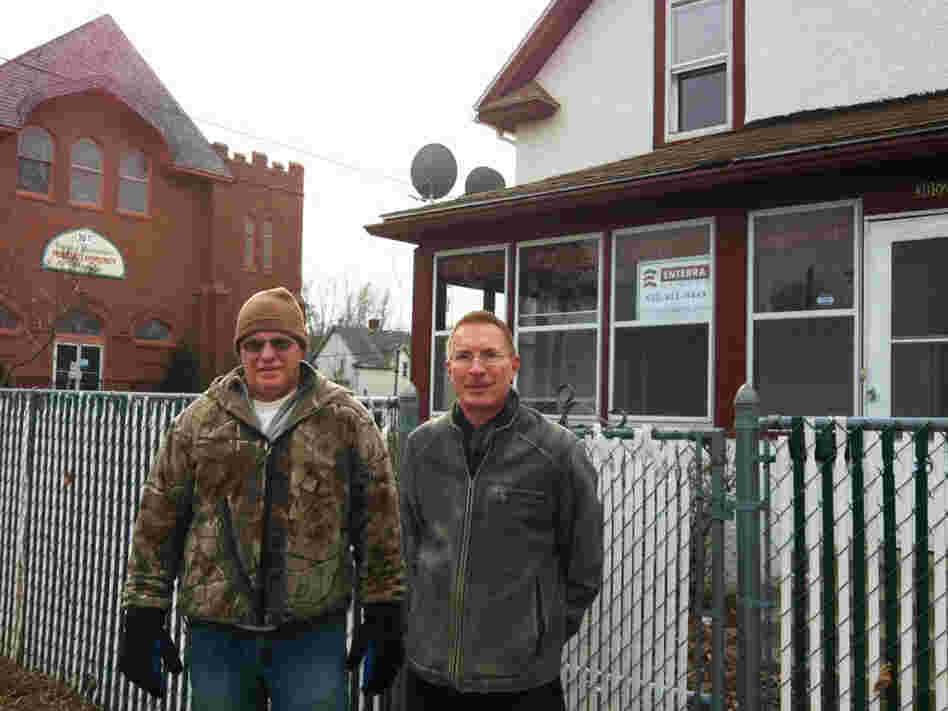 Dan Grohs (left) with real estate agent Pat Paulson in front of a foreclosed Minneapolis home. Grohs hopes to buy the house with cash.