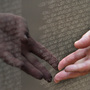 A visitor touches names engraved on a traveling half-scale replica of the Vietnam Veterans Memorial in Washington, D.C.