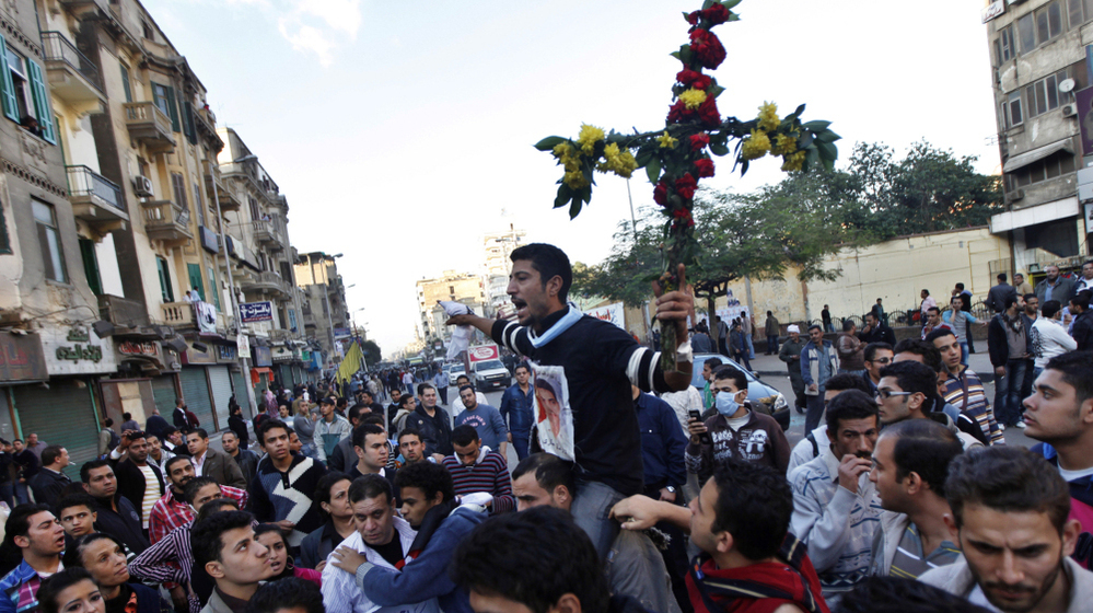 A Coptic Christian man holds a cross made of flowers during a clash between Christians and Muslims in Cairo in November. Relations are becoming more strained between the two communities, and there has been periodic violence.