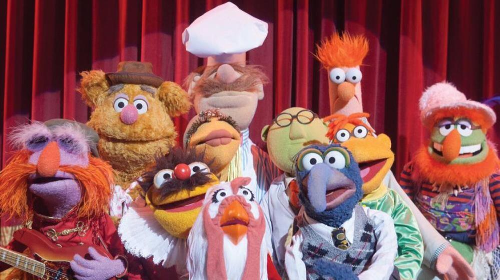 The cast of The Muppets includes (left to right) Floyd Pepper, Fozzie Bear, Lew Zealand, Janice, Swedish Chef, Camilla The Chicken, Dr. Bunsen Honeydew, Gonzo, Scooter and Beaker.
