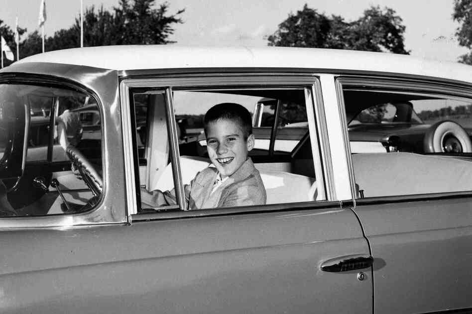 A young Mitt sits behind the wheel of his father's Rambler. 