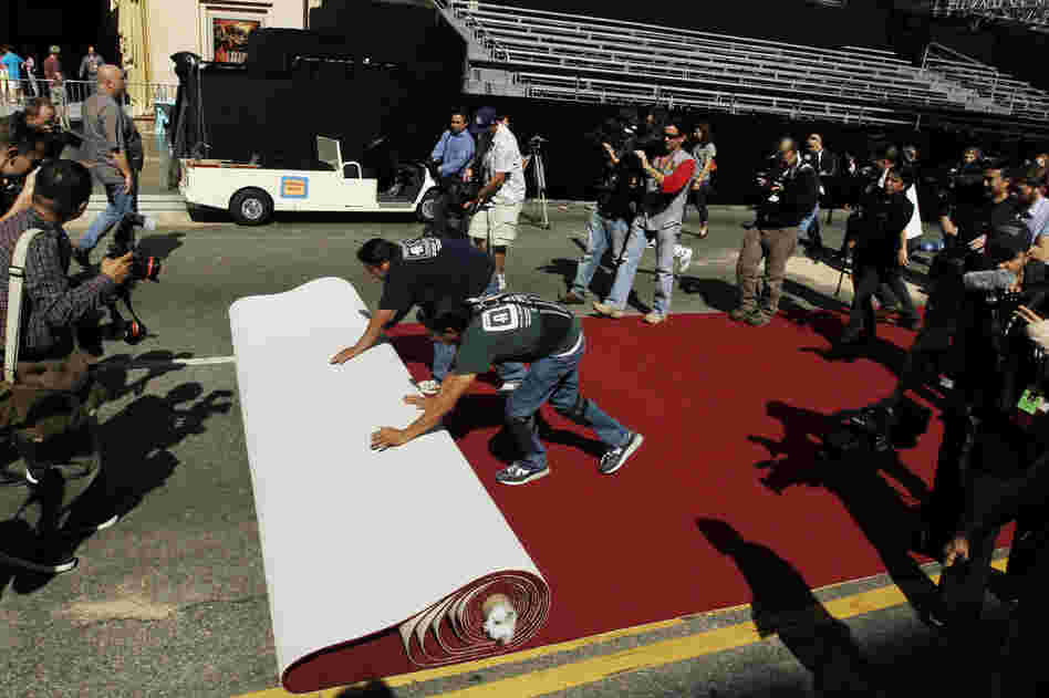 Workers roll out the red carpet as press photographers clamor to capture the moment as Oscar night approaches. 