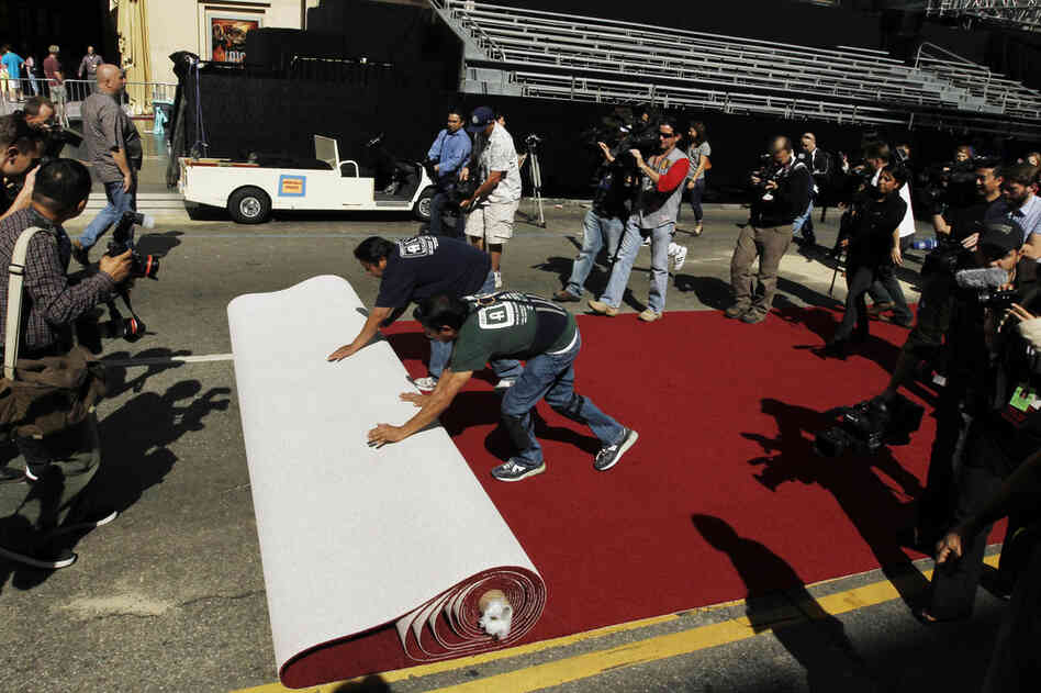 Workers roll out the red carpet as press photographers clamor to capture the moment as Oscar night approaches. 
