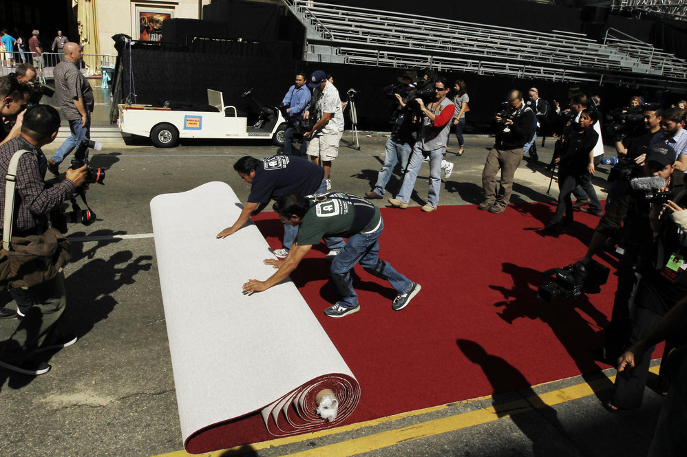 Workers roll out the red carpet as press photographers clamor to capture the moment as Oscar night approaches. 