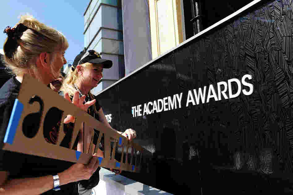 Crew members apply a fixture onto a wall of the red carpet for this year's Academy Awards hosted by Billy Crystal. 